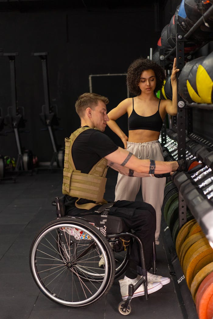 An inclusive gym workout featuring a trainer assisting a wheelchair user.